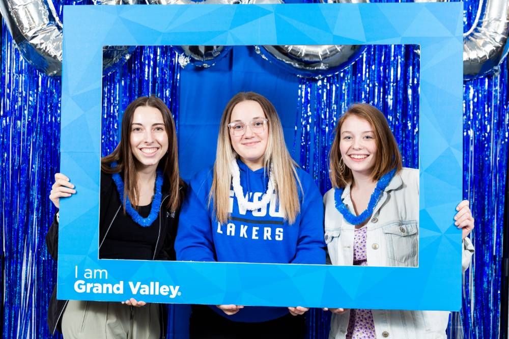 three students pose in blue frame